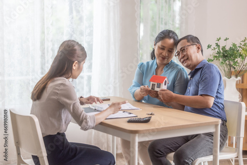 Elderly couples satisfying retirement home purchase with contract and key handover from a saleswoman