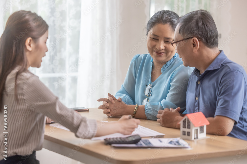 Elderly couples satisfying retirement home purchase with contract and key handover from a saleswoman Elderly couples satisfying retirement home purchase with contract and key handover from a saleswoman