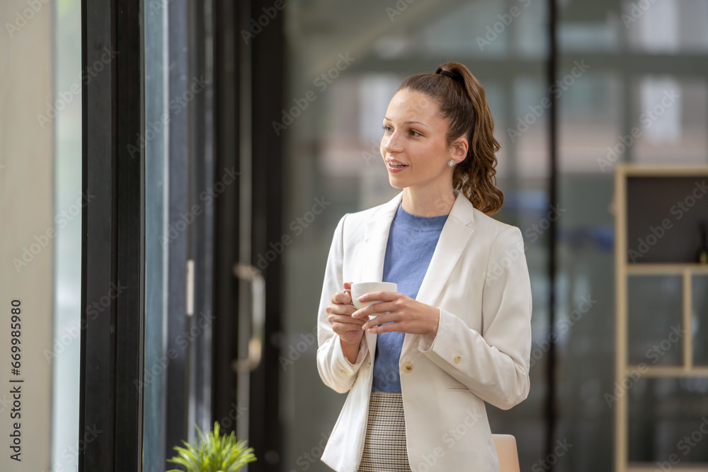 Portrait of a smart businesswoman leaning on a table. Sip coffee and relax while looking out the window. Portrait of a smart businesswoman leaning on a table. Sip coffee and relax while looking out the window.