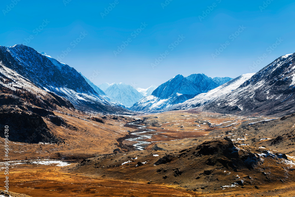 View of the Akkol river valley with snow-capped mountain peaks on the horizon in autumn. Altai republic, Russia