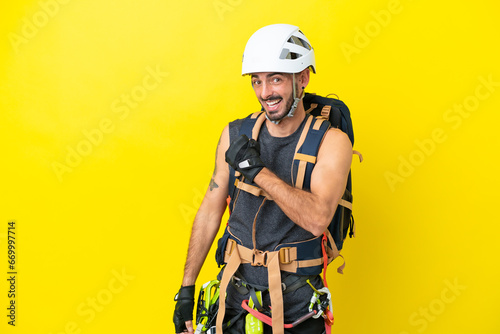 Young caucasian rock climber man isolated on yellow background celebrating a victory