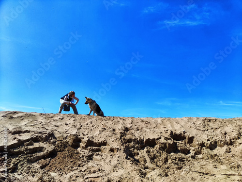 Dog German Shepherd and woman on large sandy mountain or dune in nature in a summer, spring, autumn day. Russian eastern European dog veo and the mistress, trainer outside and outdoors during training