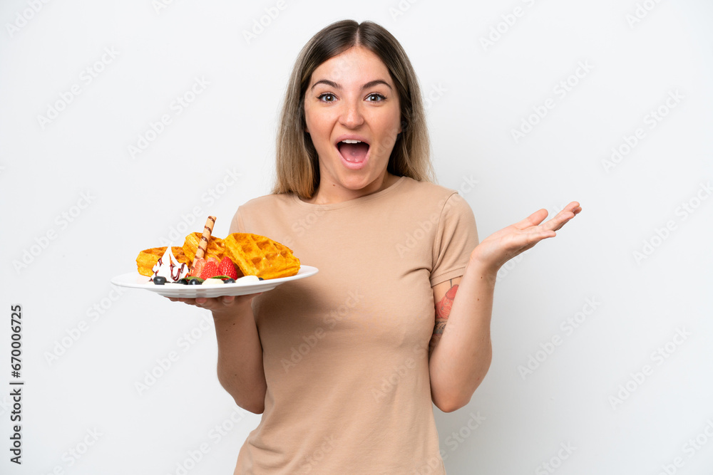 Young Rumanian woman holding waffles isolated on white background with shocked facial expression Young Rumanian woman holding waffles isolated on white background with shocked facial expression