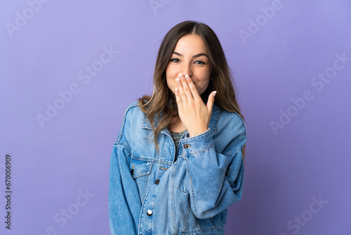 Young Romanian woman isolated on purple background happy and smiling covering mouth with hand