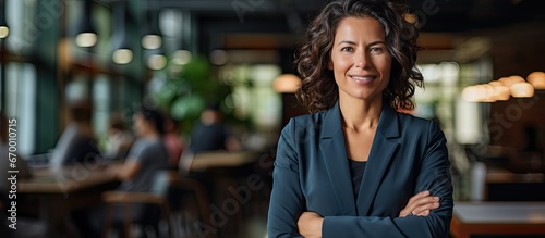 Confident senior female businesswoman smiling with crossed arms professional background