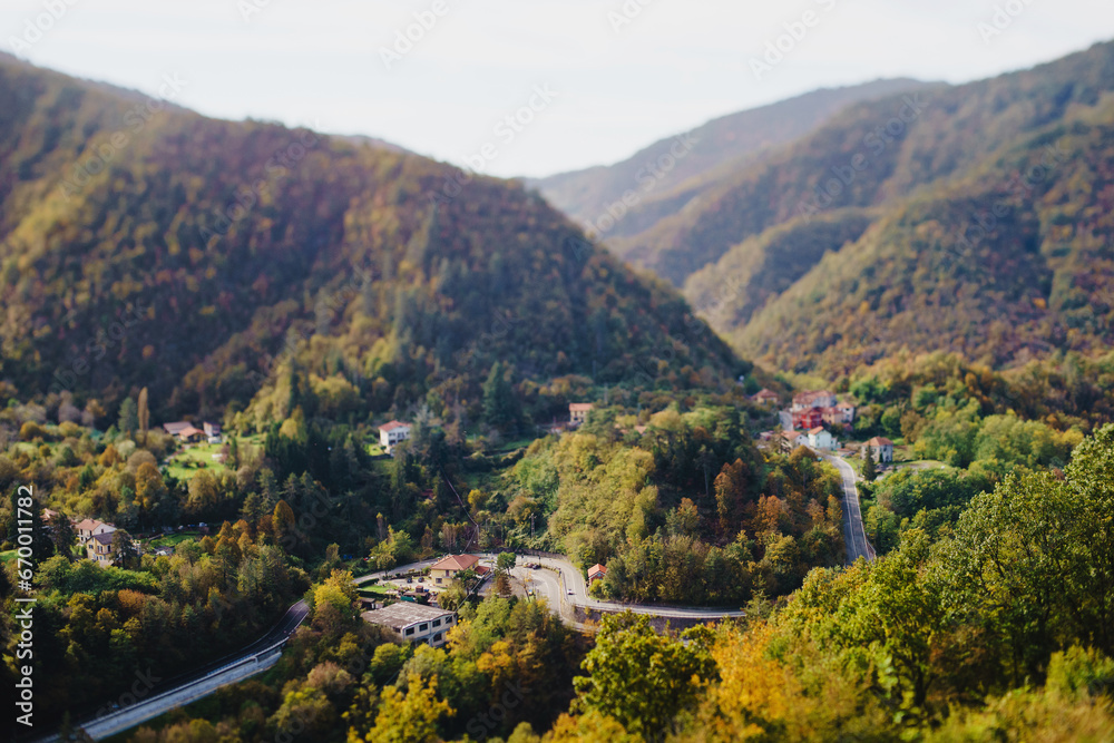 Panoramic view from above, from the throne to the valley in the mountains. A small village in the Alps. Colored houses, tiled roofs, a road and a river. Europe