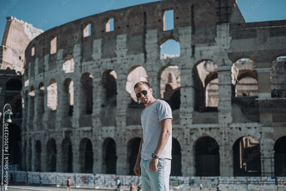 Attractive young man in Rome standing in front of the Colosseum, looking at camera