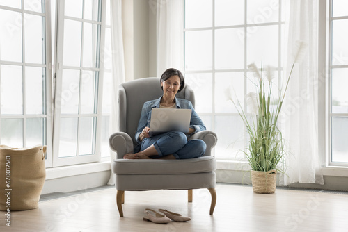 Free Download Satisfied mature woman resting with laptop rest on cozy armchair, enjoy carefree pastime on internet, choose goods, buying electronic services using marketplace, easy and comfortable modern tech usage - GFXLoad