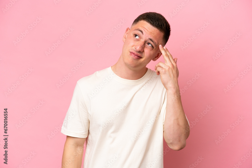 Young Brazilian man isolated on pink background with problems making suicide gesture Young Brazilian man isolated on pink background with problems making suicide gesture