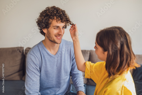 Portrait of young happy couple in love. Woman is playing with man's curly hair.