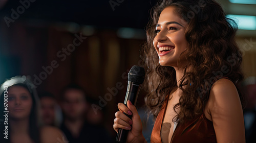 a smiling woman holding a microphone while speaking at an event