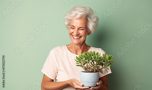 Radiant senior woman cradles a potted plant.