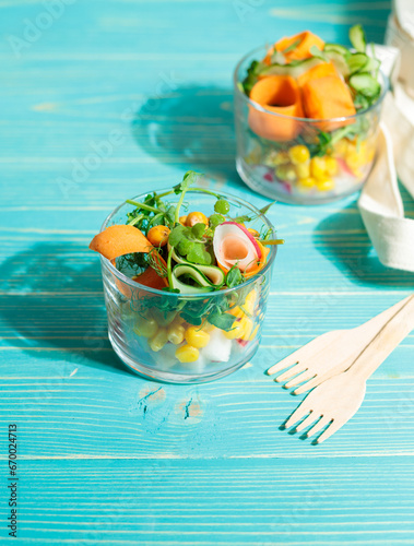 Two servings of fresh vegetables, a healthy salad or snack. Close-up on a blue wooden background.