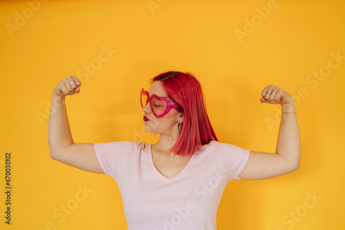 Woman wearing heart shaped sunglasses flexing muscles photo