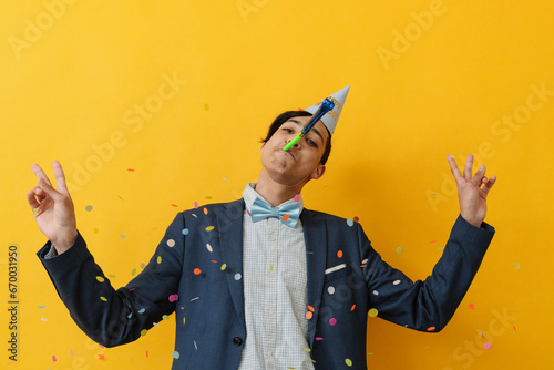 Young man gesturing peace sign and blowing party horn photo