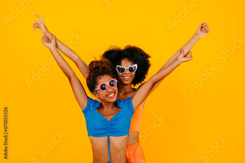 Carefree friends with arms raised against yellow background photo