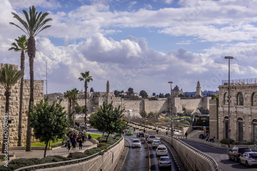 The road traffic on Jerusalem highway going along the walls of the Old town, with the palm trees, and cloudy sky, in Israel.