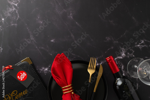 Dine-in on Black Friday theme. Overhead shot of plates, price tag reading "sale," tableware, crimson napkin with ring, order menu, wine bottle, glass on black marble backdrop with room for text or ad