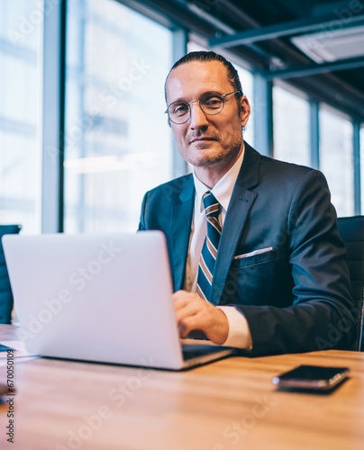 caucasian man in spectacles sitting at desktop with laptop