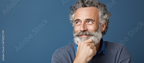 Thoughtful middle aged man with a beard considering a question with a doubtful expression and a smile