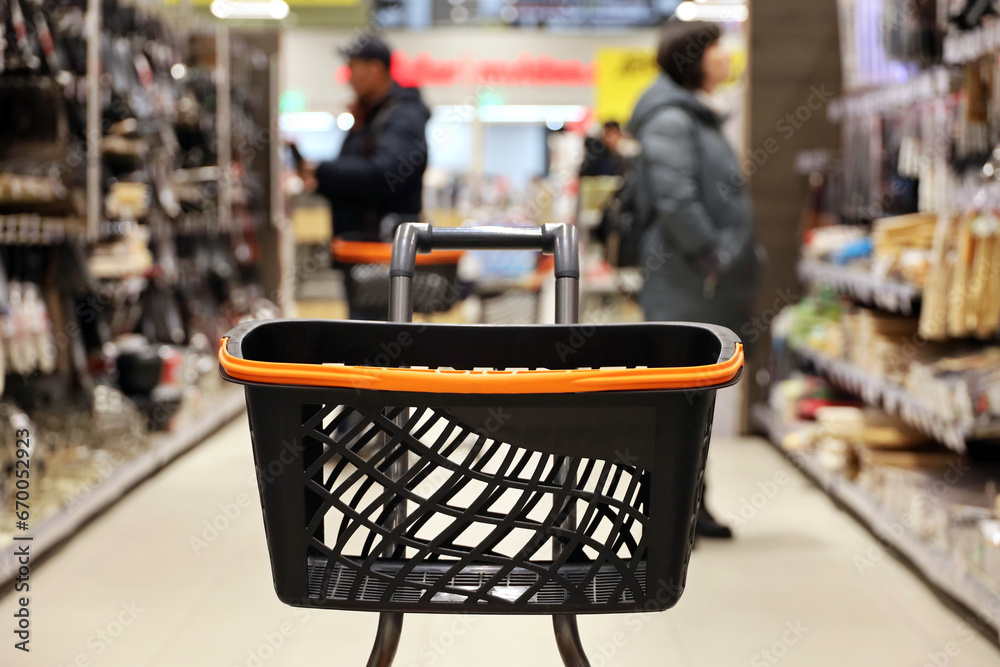 Empty shopping cart in a supermarket on customers background. Choosing goods in a shop Empty shopping cart in a supermarket on customers background. Choosing goods in a shop