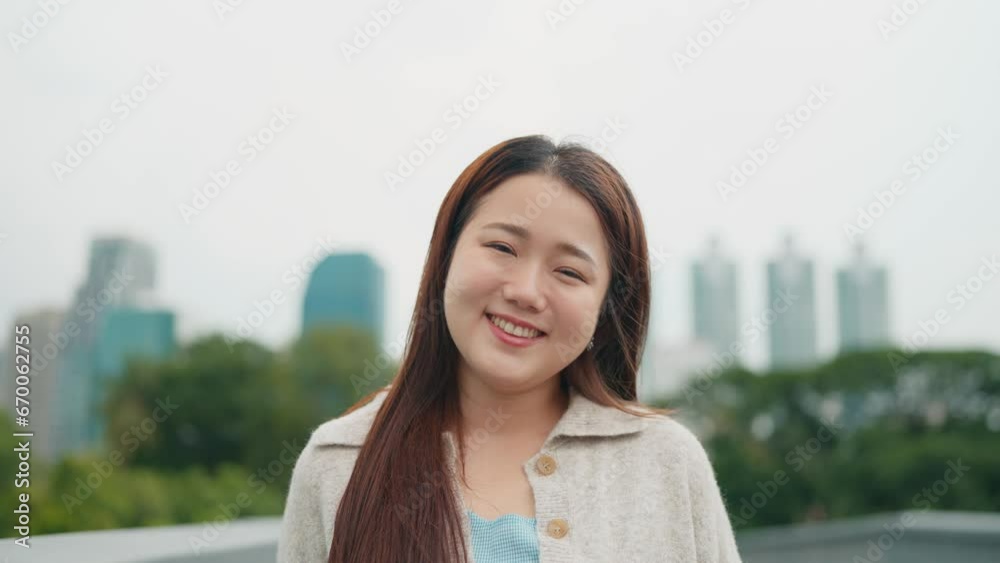 Close up portrait of a relaxed asian woman standing outdoors at city street smiling to camera. Beautiful Attractive Asian female looking at camera and smile happiness and comfortable at public park Close up portrait of a relaxed asian woman standing outdoors at city street smiling to camera. Beautiful Attractive Asian female looking at camera and smile happiness and comfortable at public park
