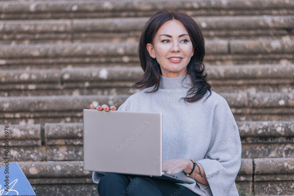 Woman sitting on a staircase typing on a computer Woman sitting on a staircase typing on a computer