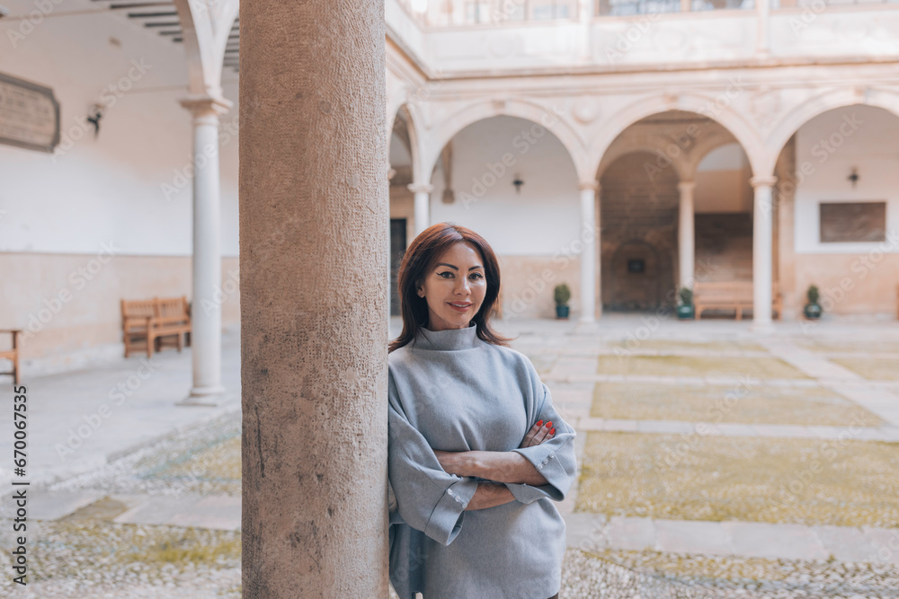 Woman with arms crossed leaning on a column Woman with arms crossed leaning on a column