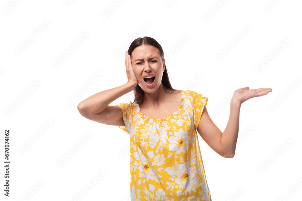 brunette young woman dressed in a yellow summer outfit covered her ear and screamed brunette young woman dressed in a yellow summer outfit covered her ear and screamed