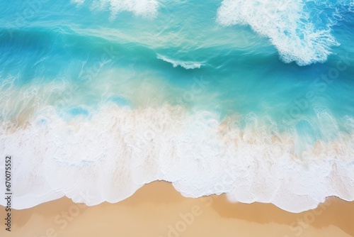 Aerial view of azure blue ocean waves crashing on a pristine white sandy beach.