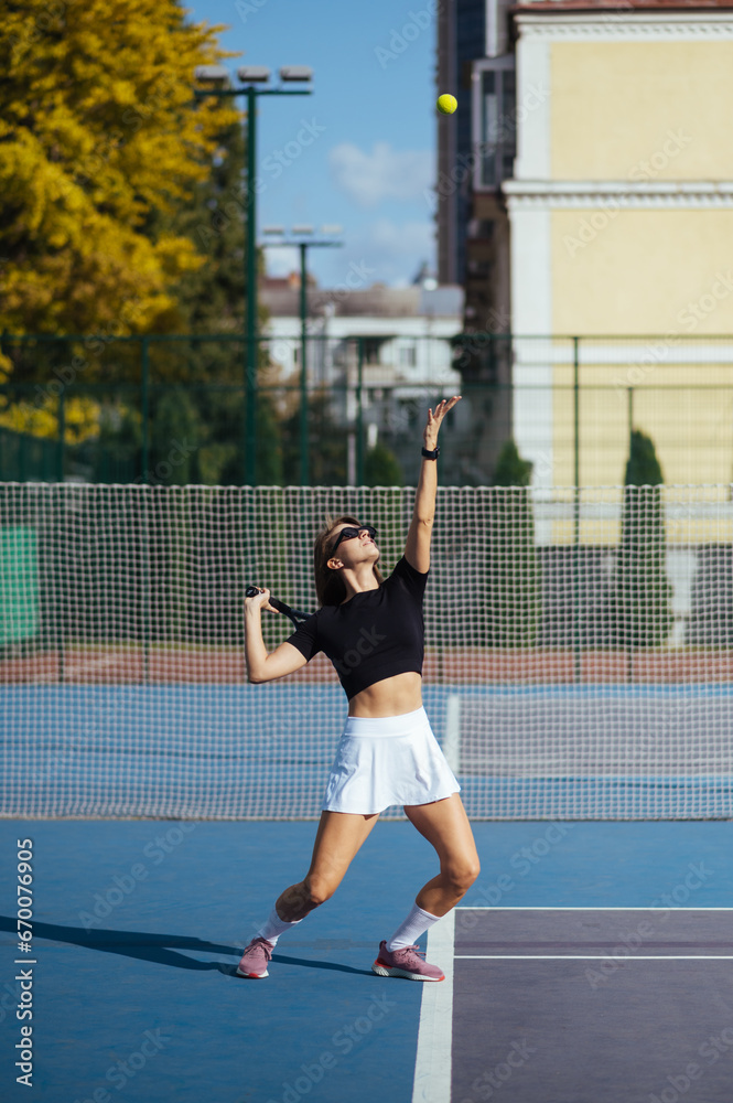 Sporty woman plays tennis on the court, serves the ball.
