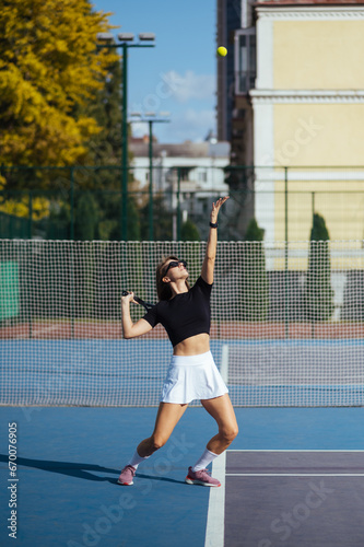 Sporty woman plays tennis on the court, serves the ball.