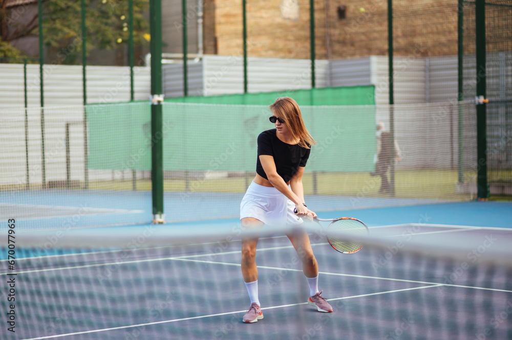 Attractive woman playing tennis on the court on a day off. Tennis as a hobby