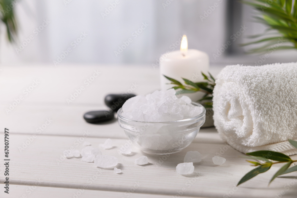 composition with sea salt, towel and candle on white wooden table at spa centre. copy space