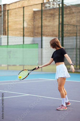 Sporty beautiful woman playing tennis on the court. Vertical photo in full height. Tennis concept.