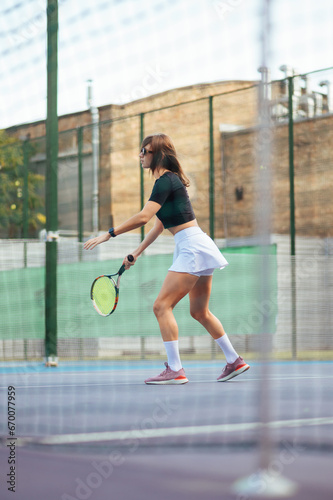 Photo of a sporty woman training in a game of tennis on the court. © bodnarphoto