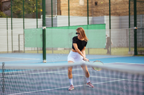 Attractive woman playing tennis on the court on a day off. Tennis as a hobby © bodnarphoto