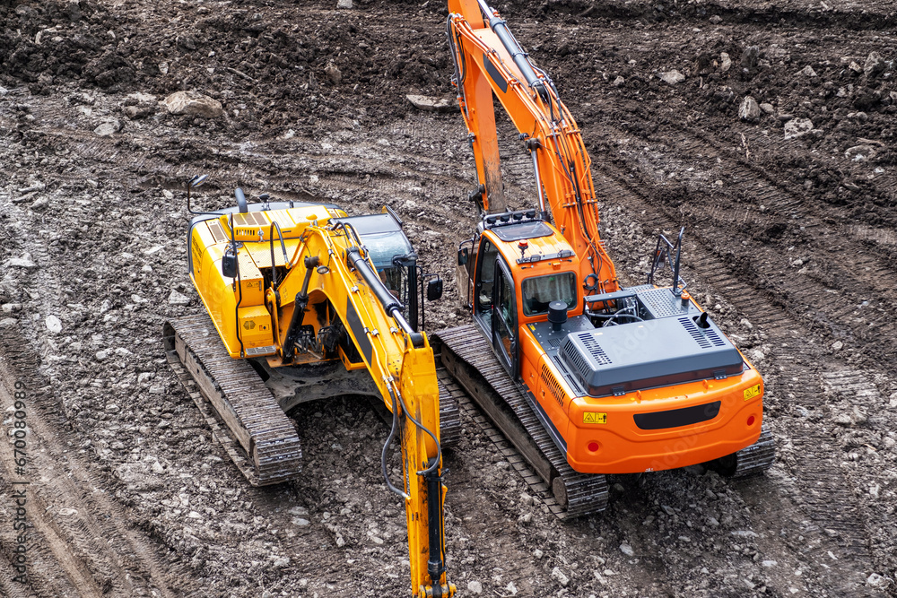 A yellow excavator works in the mountains. Construction of roads and houses in beautiful mountains. A yellow excavator works in the mountains. Construction of roads and houses in beautiful mountains.