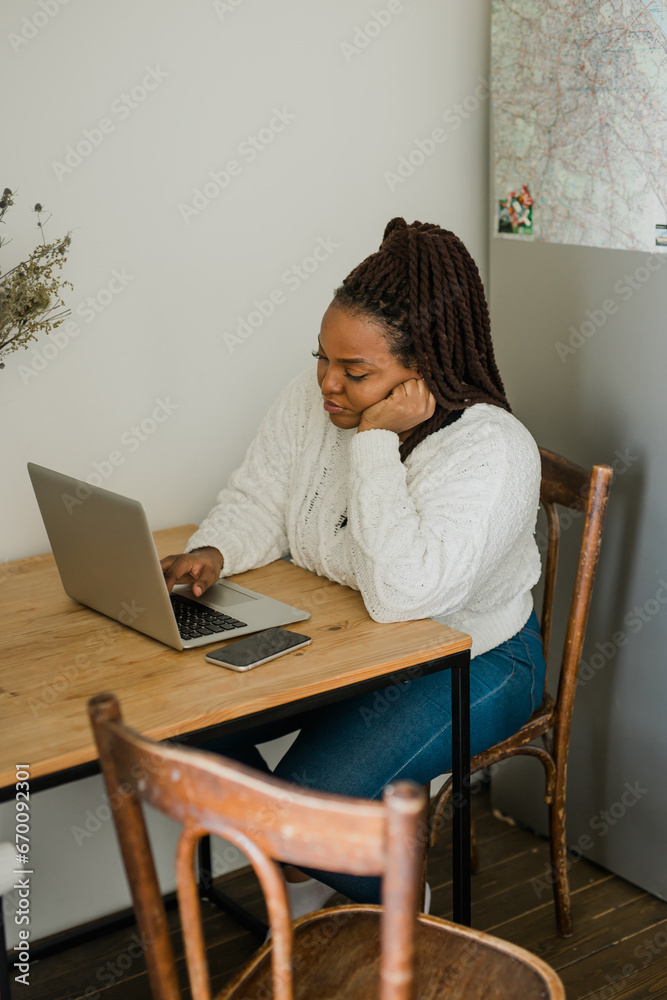 Cheerful african american woman using laptop while sitting on chair in living room - student, video call and working at home concept Cheerful african american woman using laptop while sitting on chair in living room - student, video call and working at home concept