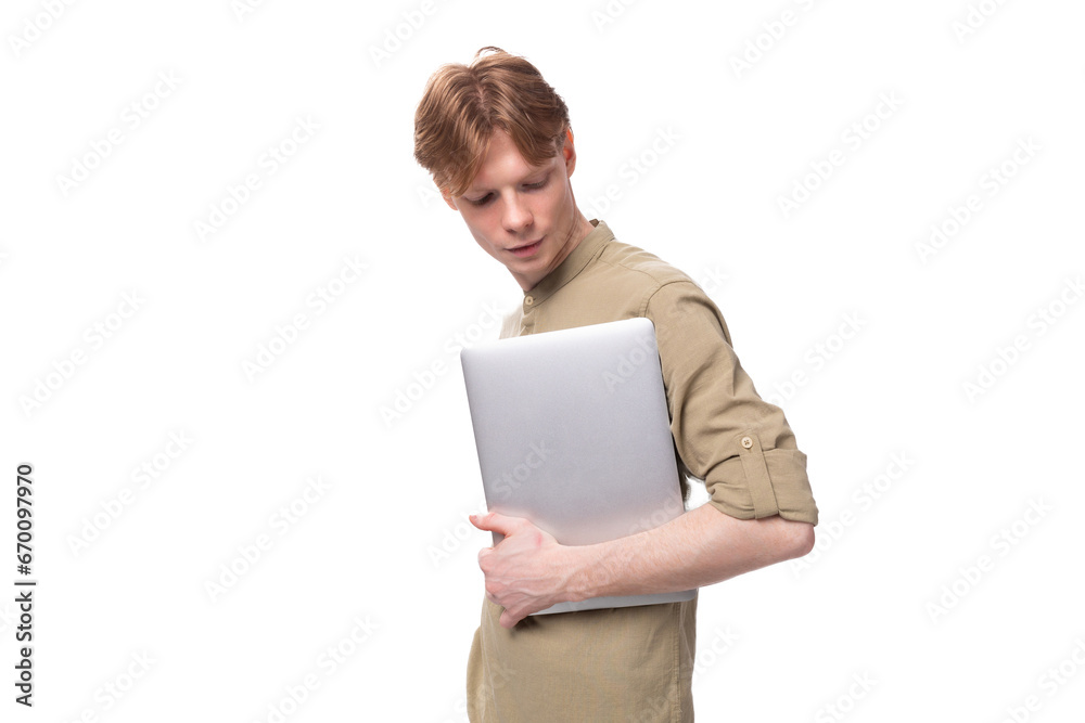young handsome red-haired man in glasses and a shirt holds a laptop for remote work young handsome red-haired man in glasses and a shirt holds a laptop for remote work