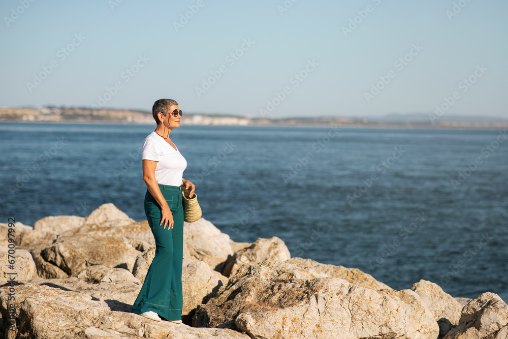 Woman wandering by sea lagoon, standing near sea shore outside