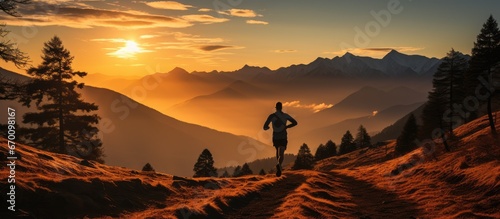 silhouette of single trail runner man, at sunrise while running in mountains with steep path