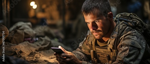 Using a cell phone during boot camp warfare, a military soldier in the middle. A soldier in a historical reenactment using a texting smartphone that is out of date. photo
