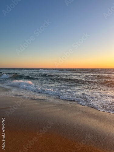 Orange sea horizon, sandy coastline, evening seascape reflection, pastel colors © Oksana