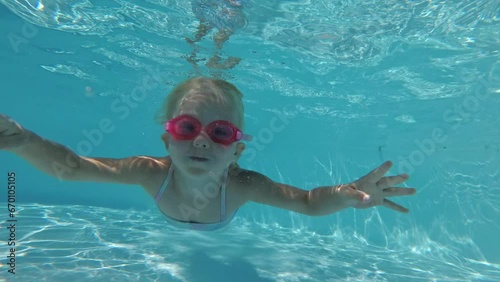 A 5-year-old girl child dives and swims in a pool underwater. Sports active child swims in the pool, slow motion