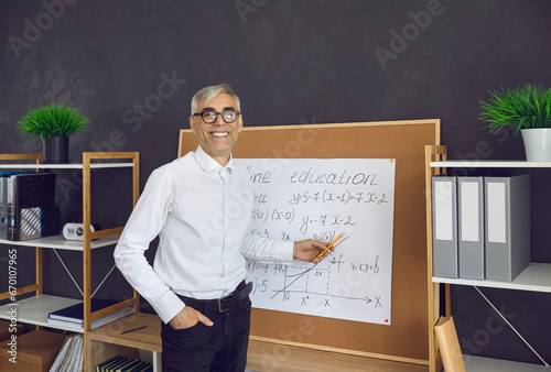 Modern education. Math teacher teaches remotely. Portrait of a friendly senior male lecturer who online explains mathematical formulas to students. Online education concept.