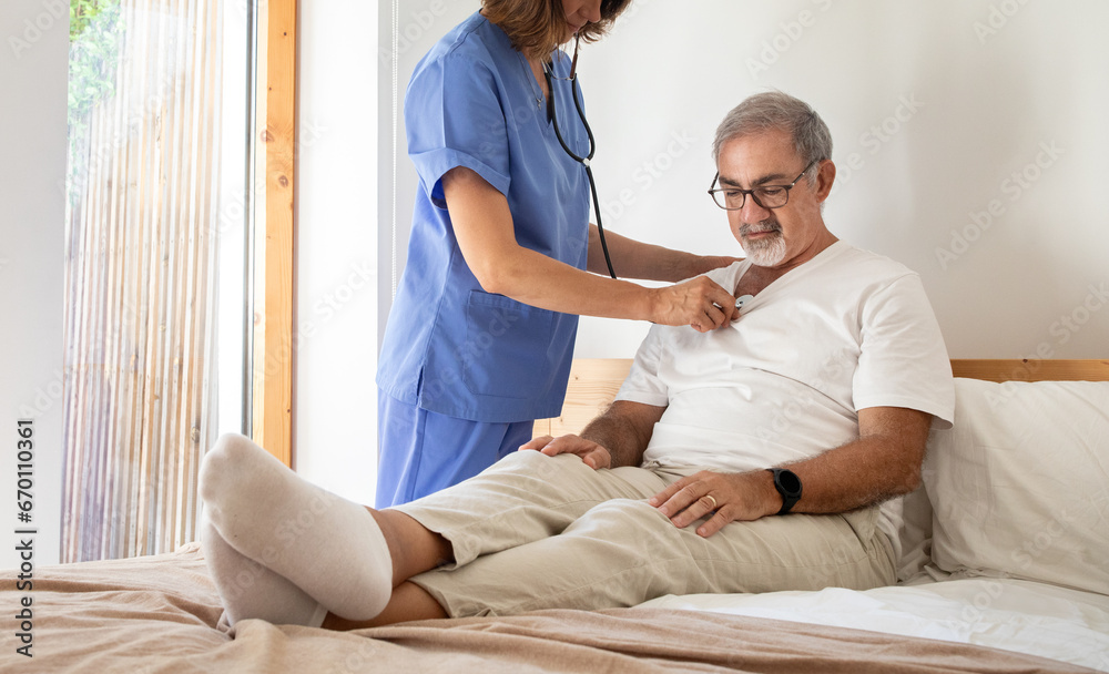 Obraz premium Millennial nurse listens with stethoscope to breath of serious senior caucasian man