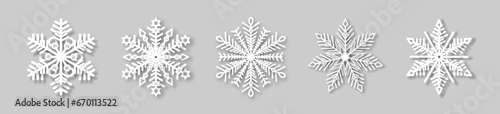 A set of white snowflakes with a paper effect and a shadow on a gray background. The element of Christmas and New Year. The symbol of winter. Vector illustration.