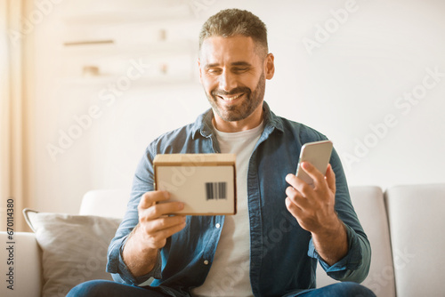 Happy middle aged man unboxing newly purchased mobile phone indoor