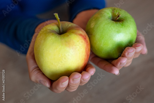 The woman holds fruits in her hand. The girl holds an apple. Apples in woman's hands. Green apples.